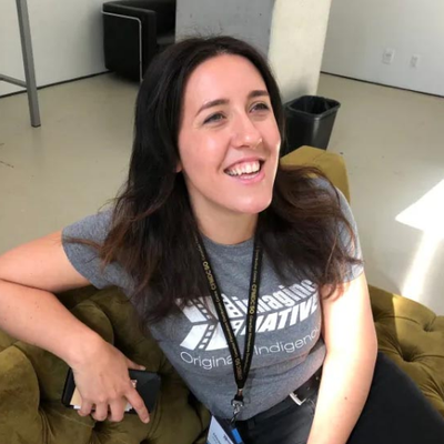 Meagan Byrne sits on a couch while smiling.